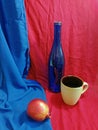 Blue bottle on red and pomegranate on blue drapery Royalty Free Stock Photo