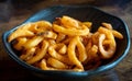 Blue bowl filled with freshly made curly fries placed on a table.