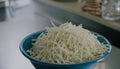 A blue bowl filled with grated cheese