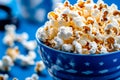 A blue bowl filled with popcorn sitting on top of a table Royalty Free Stock Photo
