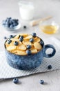 Blue Bowl of mini pancake cereal with blueberries, maple syrup and milk