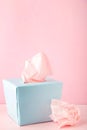 Blue box with paper tissues and used crumpled napkins on pink background Royalty Free Stock Photo