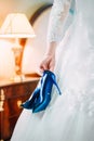 Blue bride`s wedding shoes is holding in her hand