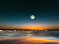 Blue bright starry sky on pink yellow sunset at sea water vawe reflection blurred light full moon moonlight  skyline  nebula natur Royalty Free Stock Photo