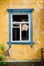 Blue broken window in old yellow abandoned house