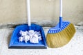 Blue broom and dustpan for house work with garbage papers on flo