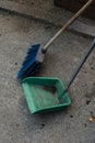 Blue broom with green trash bin on the concrete street standing still without moving. Stillness of the quarantined city