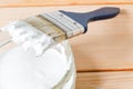 Blue brush in white paint lies on a glass jar with paint, against the background of light boards. Close-up, selective focus Royalty Free Stock Photo