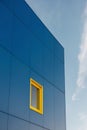 A blue building with a yellow window on the side of it. Royalty Free Stock Photo