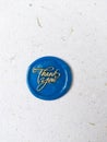 Blue button wax coin with the gold word thank you on it on a white background Royalty Free Stock Photo