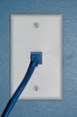 Blue cable connected to a wall outlet. Royalty Free Stock Photo