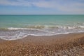 Blue calm sea, waves, sandy beach and pebbles
