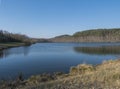 Blue calm water of forest lake, fish pond Kunraticky rybnik with birch and spruce trees growing along the shore and Royalty Free Stock Photo