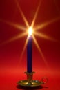 Blue candle in brass holder on red. Royalty Free Stock Photo