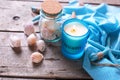 Blue candle and marine items on aged wooden background.