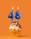 Blue candle number 48 - Birthday cupcake on orange background