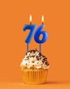 Blue candle number 76 - Birthday cupcake on orange background