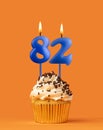 Blue candle number 82 - Birthday cupcake on orange background