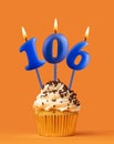 Blue candle number 106 - Birthday cupcake on orange background Royalty Free Stock Photo