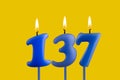 Blue candle number 137 - Birthday on yellow background Royalty Free Stock Photo