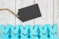 Blue candy bunnies with gift tag on weathered whitewash textured wood background