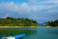 Blue canoe with floating paddles in the emerald lake with islands and forests