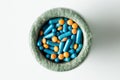 Blue capsules and orange pills with mortar pestles on white background. Royalty Free Stock Photo