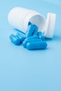 Blue capsules, pills on a blue background. Capsules in a white jar. Vitamins, nutritional supplements for women`s health Royalty Free Stock Photo