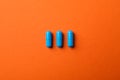 Blue capsules pills on orange background Royalty Free Stock Photo