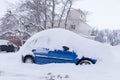 Blue car covered snow on winter town street after snowfall Royalty Free Stock Photo