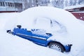 Blue car covered snow on winter town street after snowfall Royalty Free Stock Photo