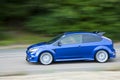 Blue car driving fast on country road