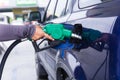 Blue car at gas station filled with fuel. Closeup woman hand pumping gasoline fuel in car at gas station Royalty Free Stock Photo