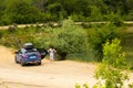 A blue car with a girl with a black roof rack stands against the background of a mountain lake with mountains and clouds Royalty Free Stock Photo