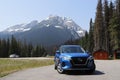 Blue car parked in the driveway of a home, with a majestic mountain landscape in the background Royalty Free Stock Photo