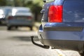 Blue car parked on sunny street, red stop lights, hook for dragging trailer, tow hitch or towbar. Royalty Free Stock Photo