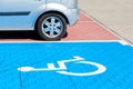 Blue car parking spot for the disabled, handicapped. Wheelchair symbol painted on the ground, parking lot vehicle space, closeup Royalty Free Stock Photo