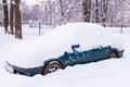 Blue car under snow in snowbank after snowfall Royalty Free Stock Photo