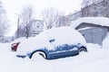 Blue car under snow on winter town street after heavy snowfall Royalty Free Stock Photo