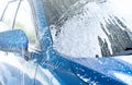 Blue car wash with white soap foam. Auto care business. Car cleaning service. Vehicle cleaning service. Foam wash car detailing. Royalty Free Stock Photo