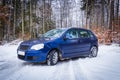 Blue car in winter forest scenery Royalty Free Stock Photo