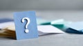 A blue card with a question mark on it is standing upright in front of other cards that are lying flat, out-of-focus behind it Royalty Free Stock Photo