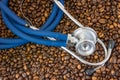 Blue cardiology stethoscope lying on the beans coffee top view. Effects of coffee and caffeine on cardiovascular system of human,