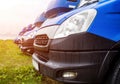 Blue cargo vans stand in a row, trucking and logistics, trucking industry and sun Royalty Free Stock Photo