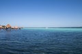 blue and blue Caribbean sea with crystal clear waters and clear sky. a bungalow with a pier in the middle of the lagoon in a coral