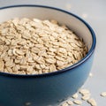 A blue ceramic bowl filled with rolled oats (Avena sativa) is placed on a smooth, light gray Royalty Free Stock Photo