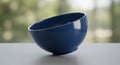 A blue ceramic bowl is positioned at an angle on a smooth, light gray surface. Its Royalty Free Stock Photo