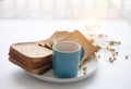 The blue ceramic coffee cup ,on white desk,with sliced bread in white dish Royalty Free Stock Photo