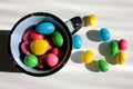 A blue ceramic cup full of colorful jelly beans on a white wooden background. Easter or Birthday treats. Royalty Free Stock Photo