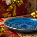 Blue ceramic plate features intricate patterns in dark blue hues. It rests on a festive Royalty Free Stock Photo